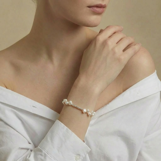 Pearl bracelet on a person wearing a white shirt against a beige background