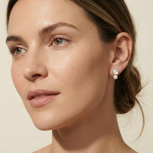 Close-up of a woman wearing pearl earrings against a beige background