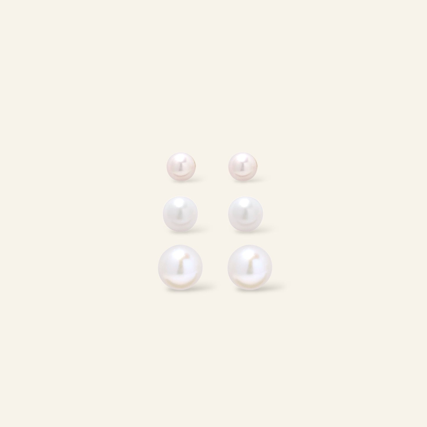 Set of pearl earrings on a light beige background