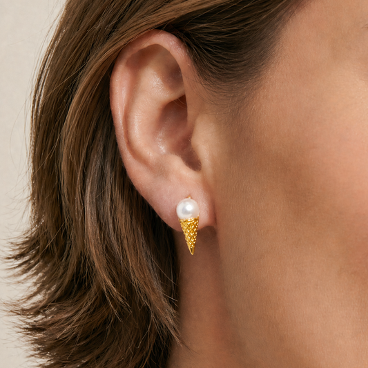 Close-up of an ear wearing a gold earring with a pearl