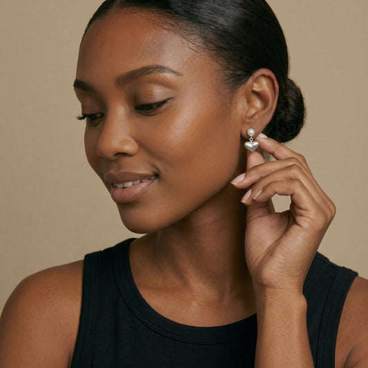 Woman wearing pearl earrings against a beige background