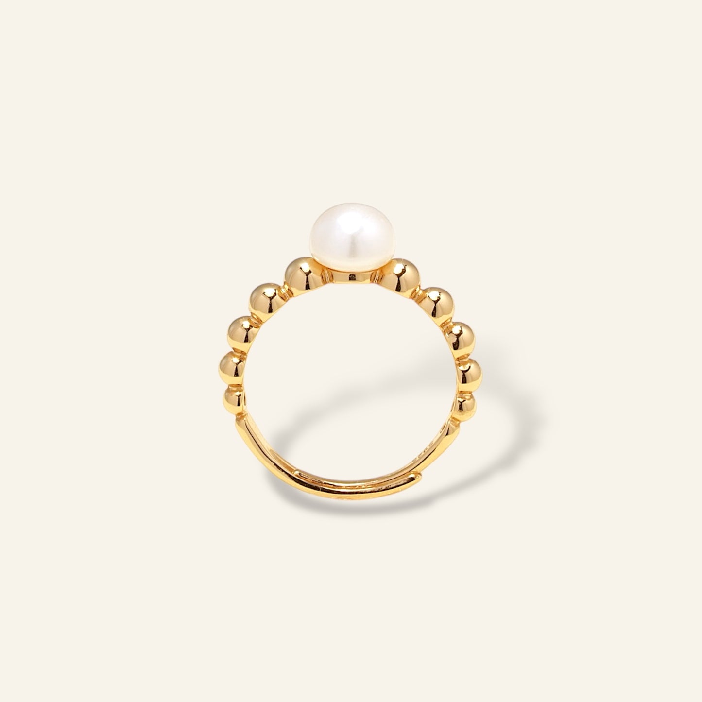 Gold ring with a pearl on a light beige background