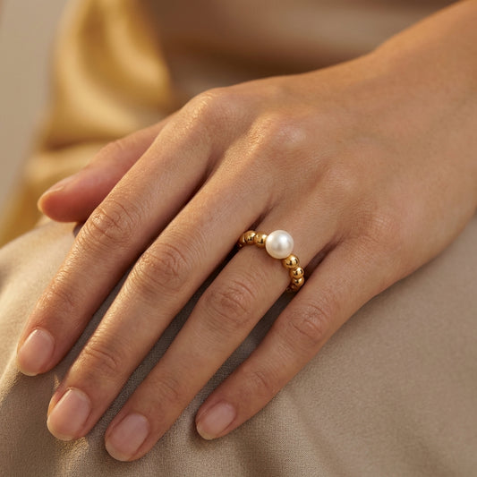 Hand wearing a gold ring with a pearl