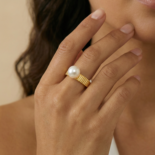 Hand wearing a gold ring with a pearl