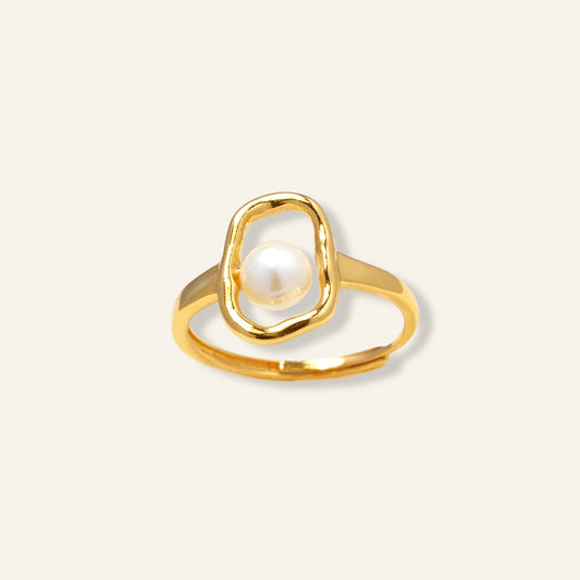 Gold ring with a pearl on a light beige background