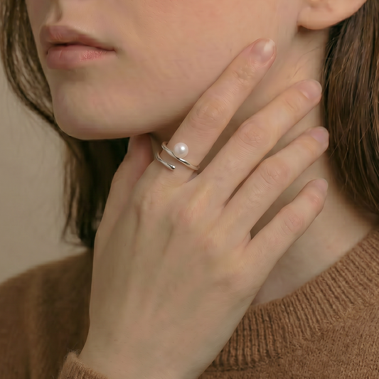 Woman wearing a pearl ring with a neutral background