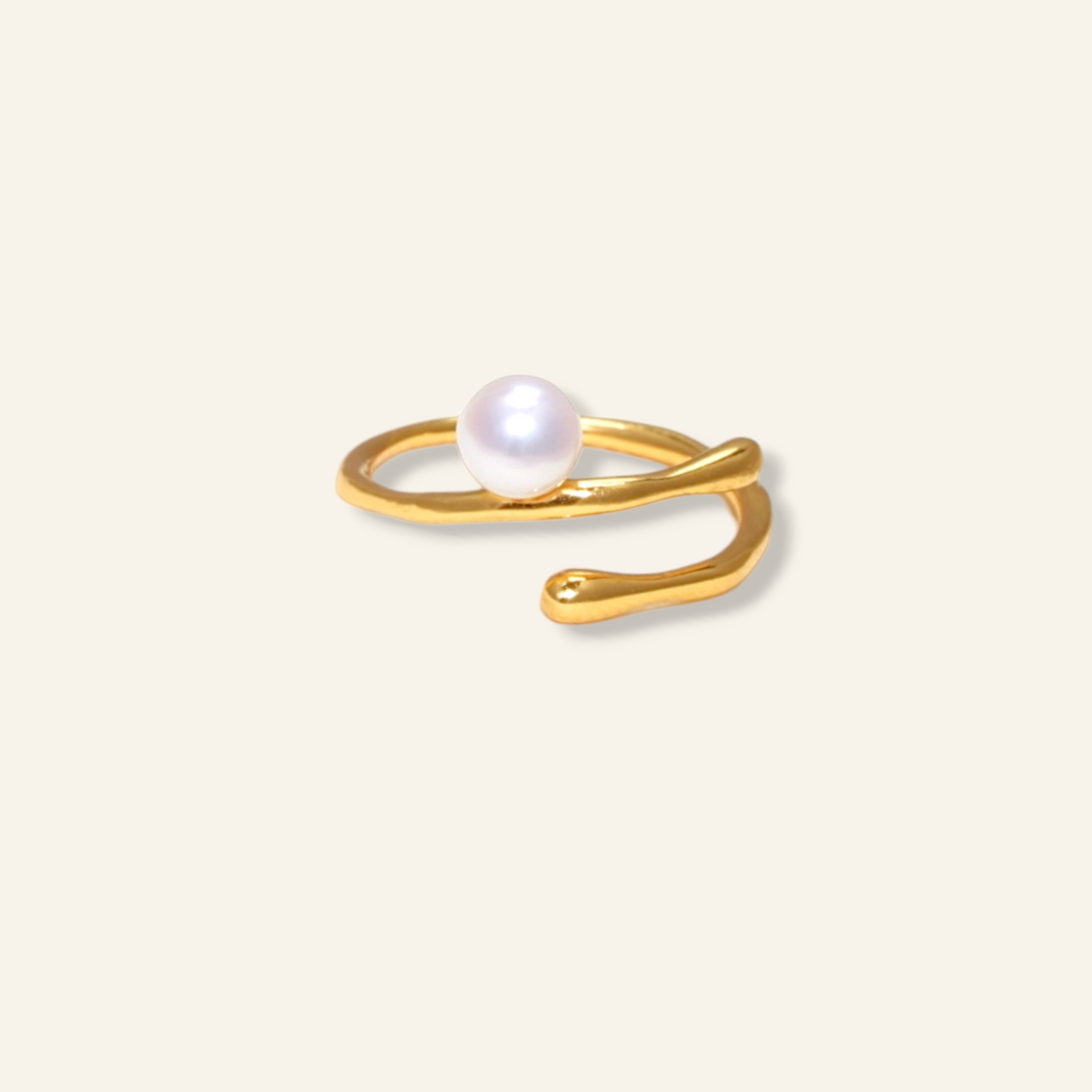 Gold ring with a pearl on a light beige background