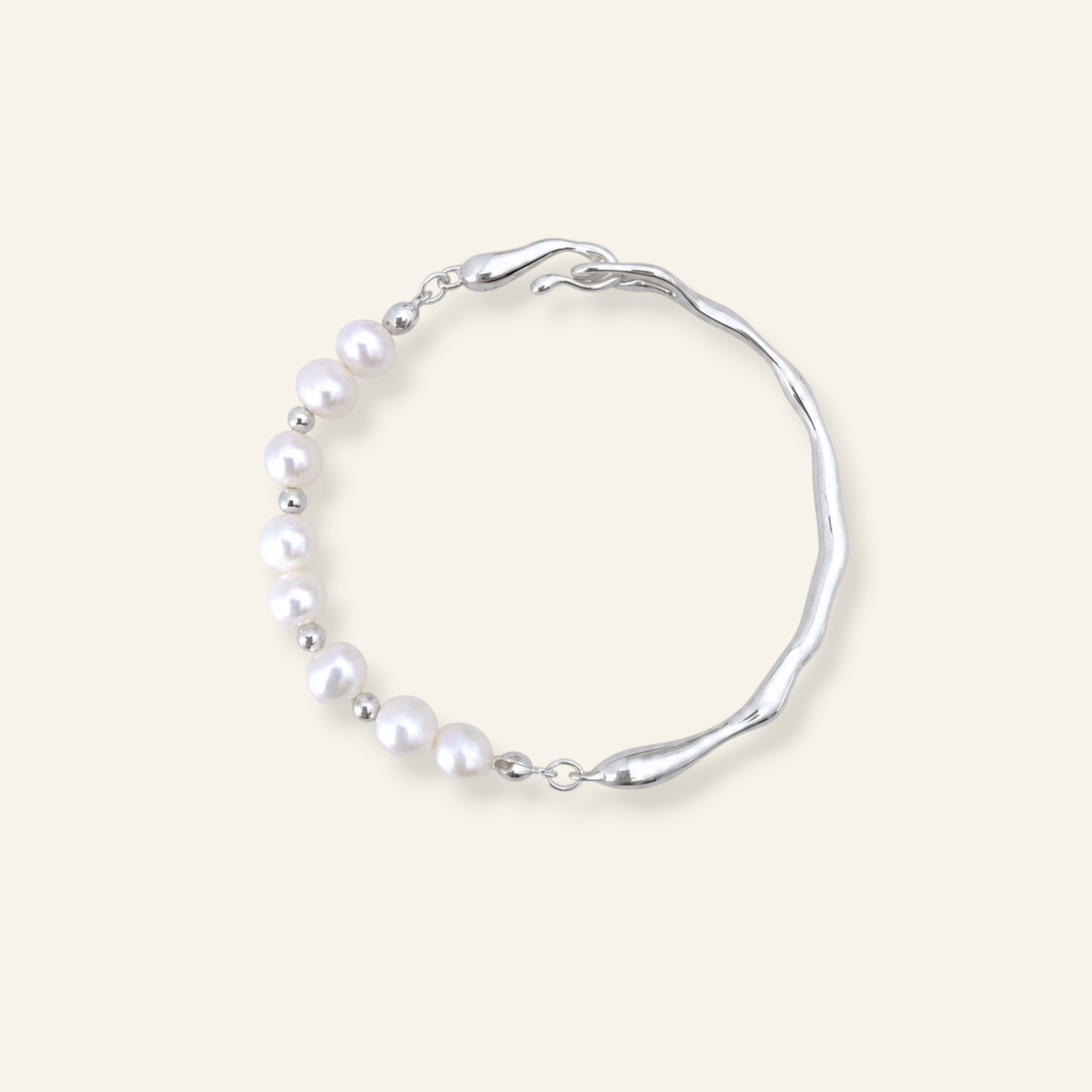 A silver-toned wavy bracelet featuring a curved row of white freshwater pearls, displayed on a solid light beige background.