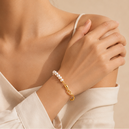 A close-up lifestyle shot of a model wearing a delicate bracelet on her wrist. The bracelet features a strand of small white pearls connected by a polished gold link chain.