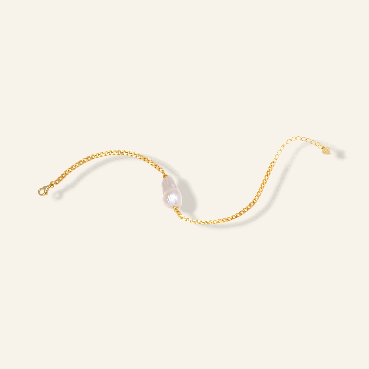 Gold chain with a pearl on a light beige background