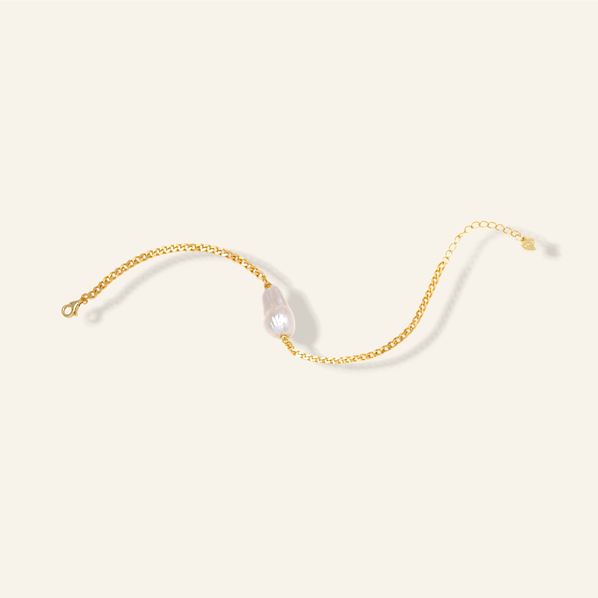 Gold chain with a pearl on a light beige background