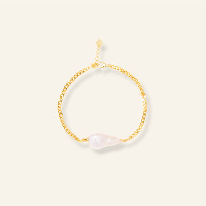 Gold bracelet with pearl on a light beige background