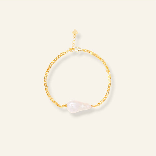 Gold bracelet with pearl on a light beige background