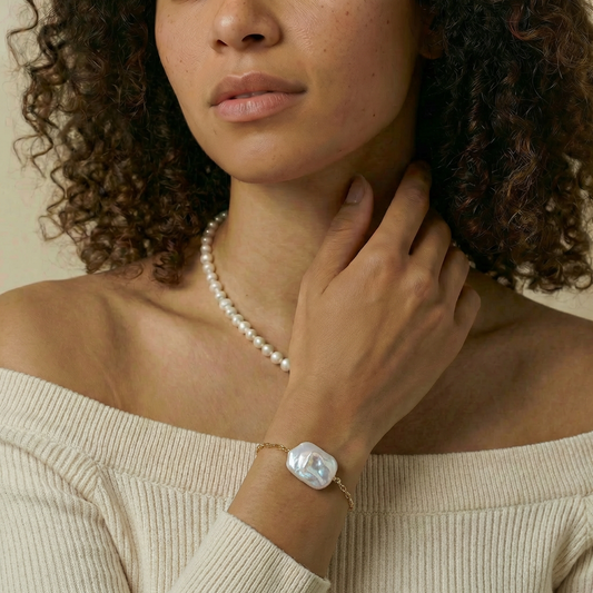 Woman wearing a pearl necklace and bracelet on a beige background