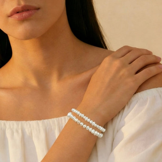 Woman wearing a pearl bracelet on a neutral background