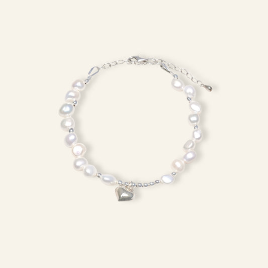 Pearl bracelet with a heart charm on a white background