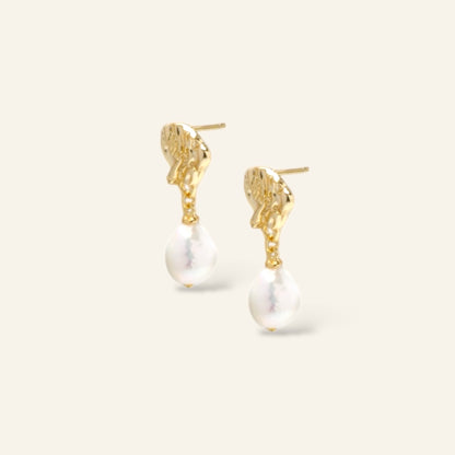Gold earrings with pearl drops on a white background