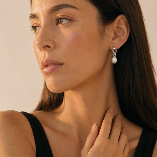 Close-up of a woman wearing pearl earrings with a neutral background