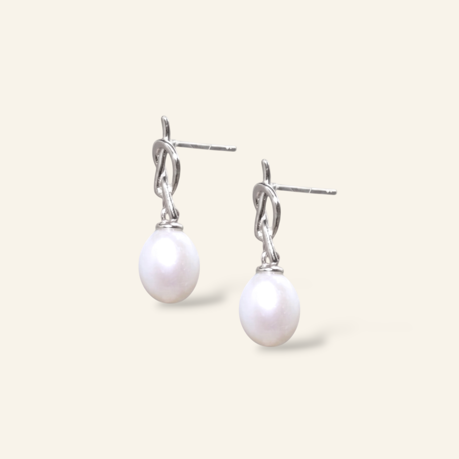 Pearl earrings with silver hooks on a light gray background