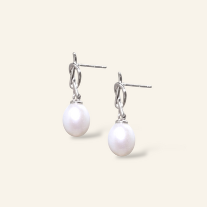 Pearl earrings with silver hooks on a light gray background