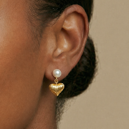  a gold heart-shaped earring with a pearl 