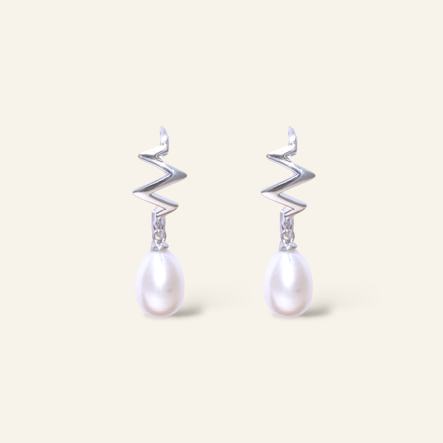 Pair of earrings with zigzag designs and pearl drops on a light background