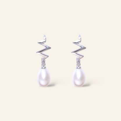 Pair of earrings with zigzag designs and pearl drops on a light background