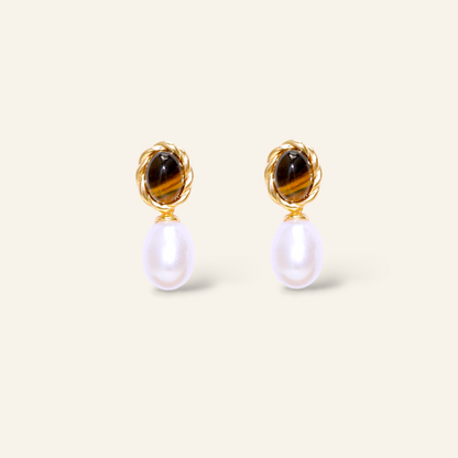 Pair of earrings with tiger eye stones and pearl drops on a light beige background