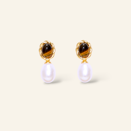 Pair of earrings with tiger eye stones and pearl drops on a light beige background