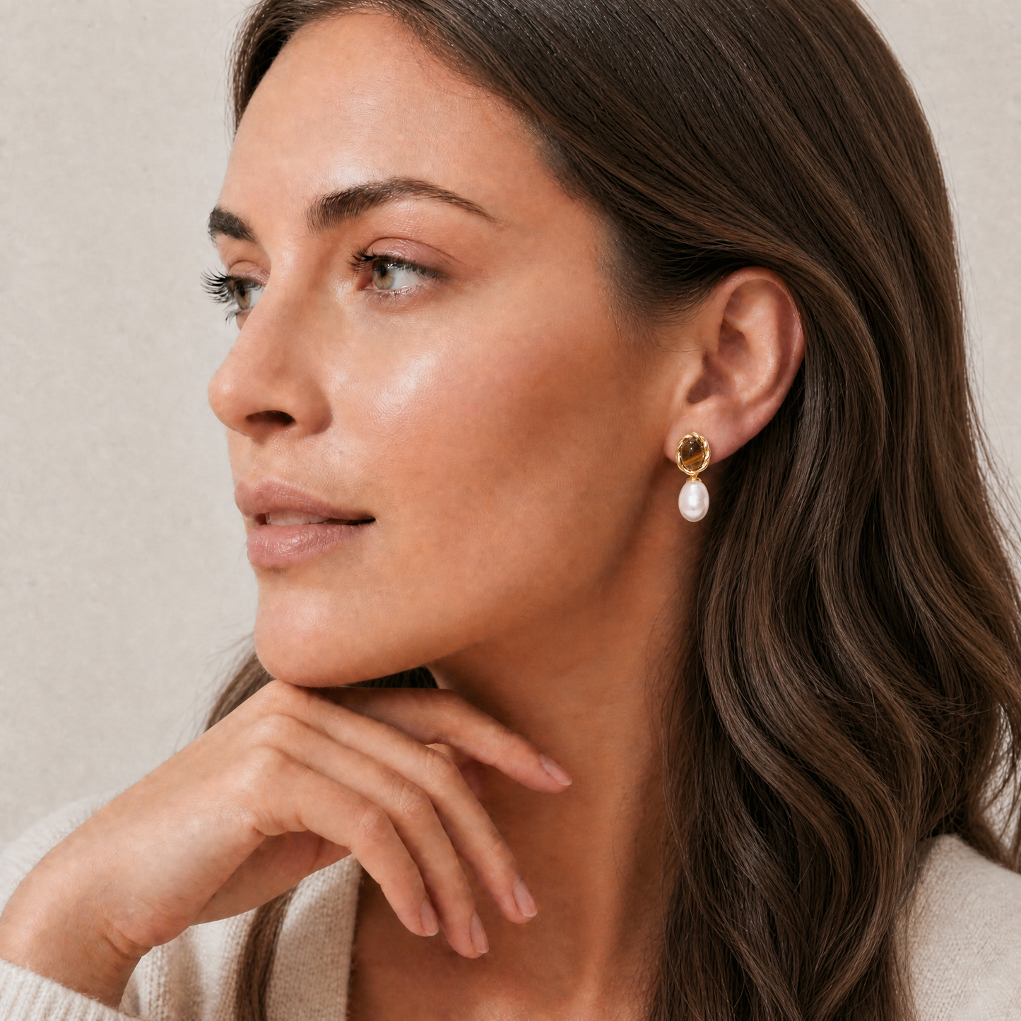 Woman wearing pearl earrings with a neutral background