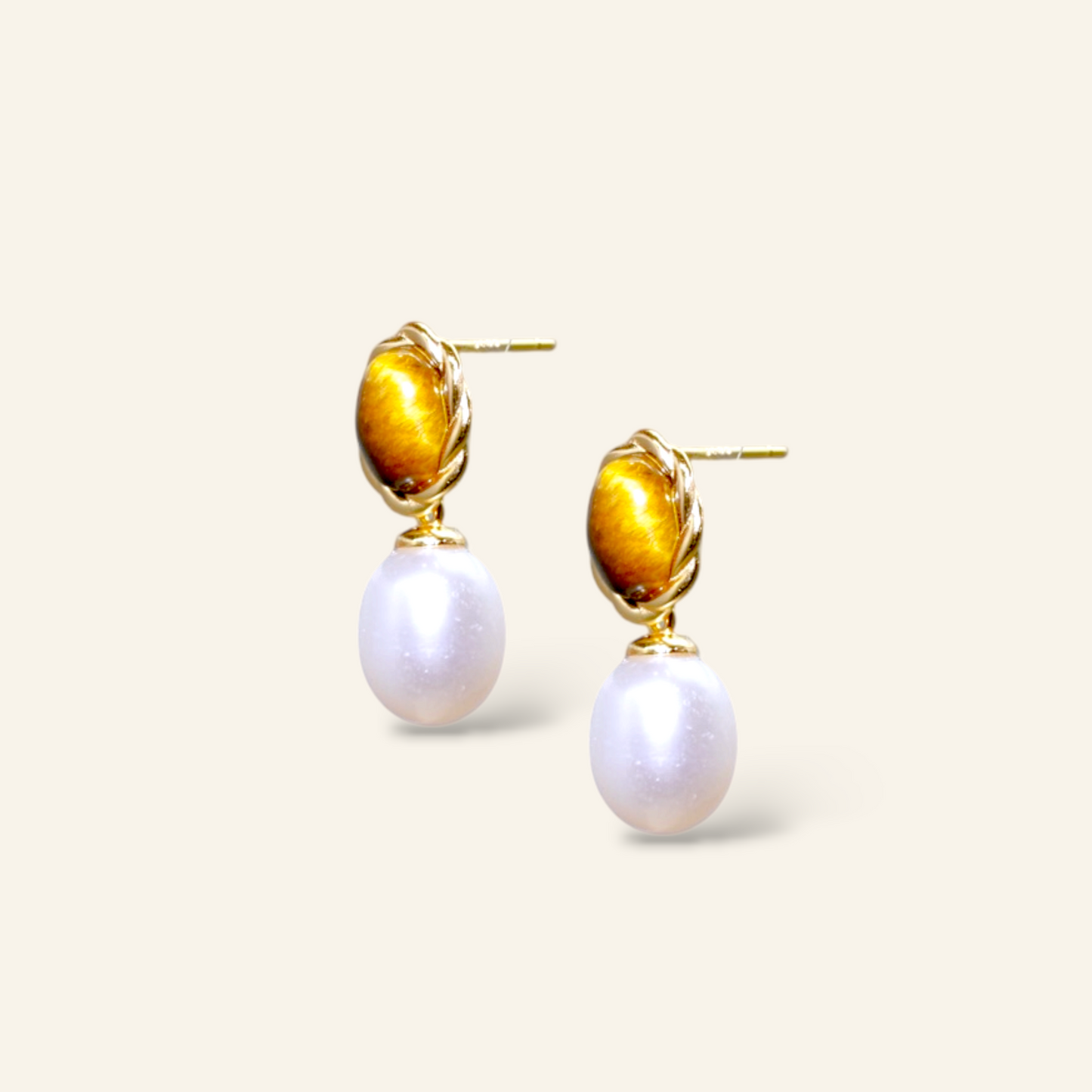Pair of earrings with gold accents and pearl drops on a light background