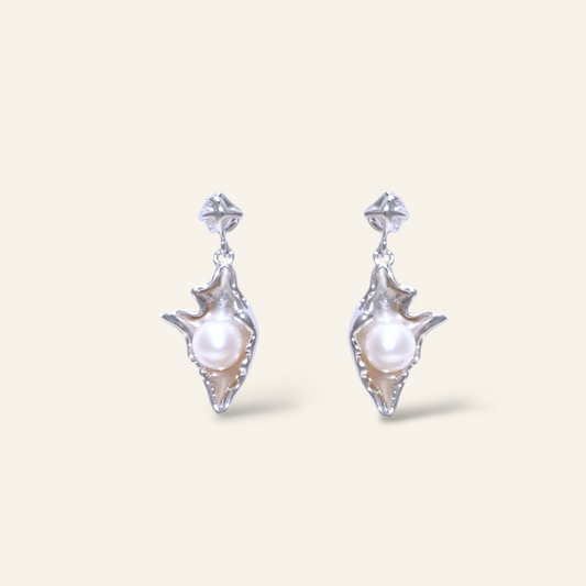 Pair of silver earrings with pearls on a light beige background
