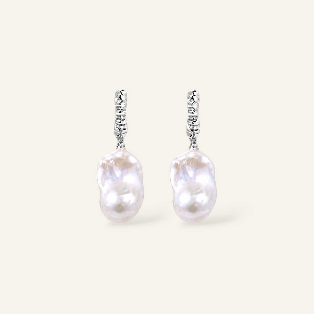 A pair of silver dangle earrings featuring irregular, lustrous white baroque pearls suspended from textured silver hooks