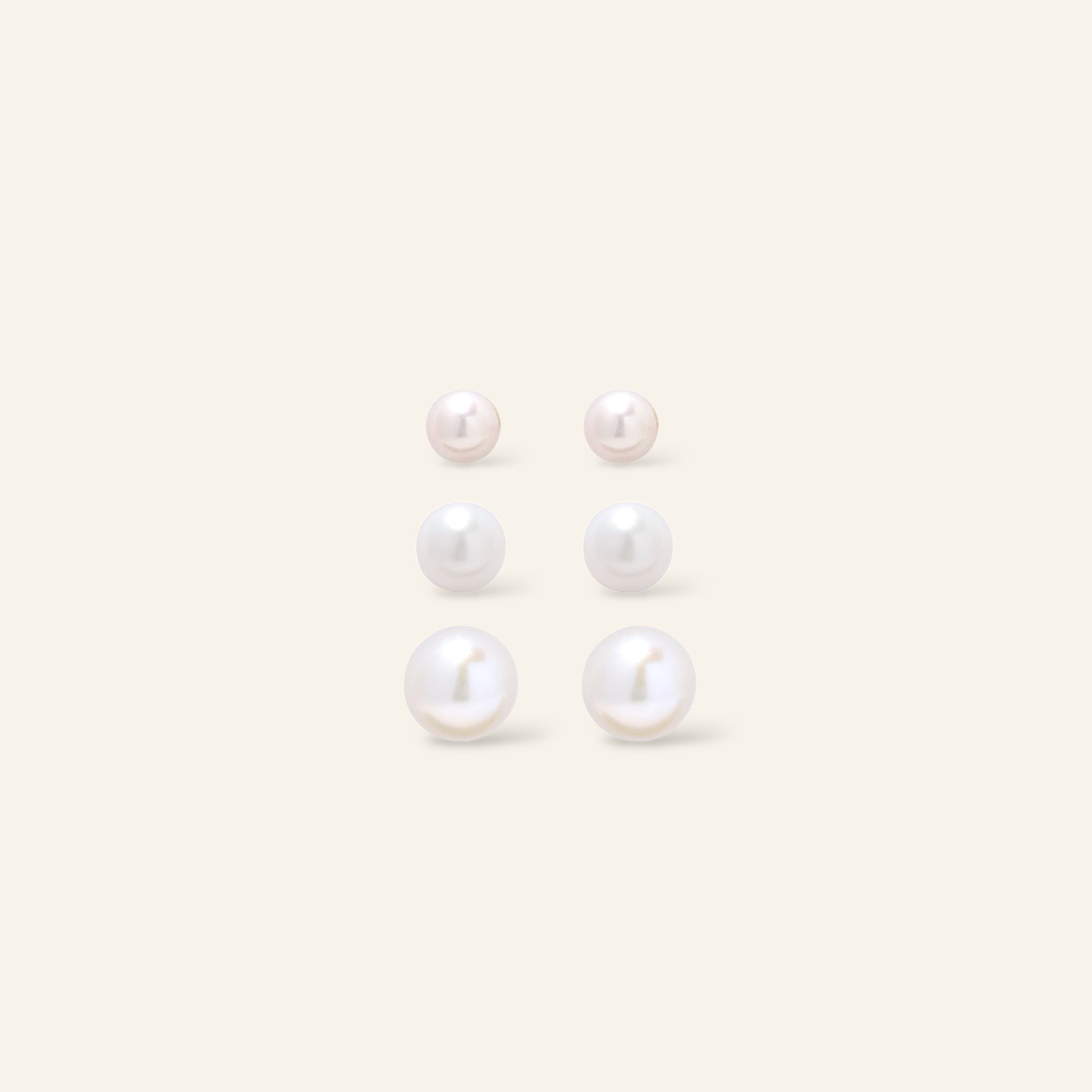 Set of pearl earrings on a light beige background