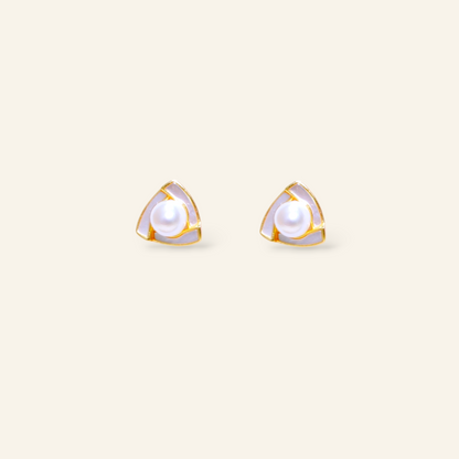 Pair of gold-trimmed pearl stud earrings on a light beige background