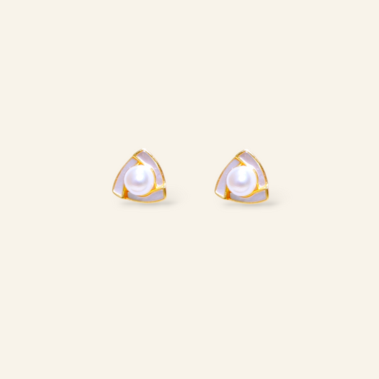 Pair of gold-trimmed pearl stud earrings on a light beige background