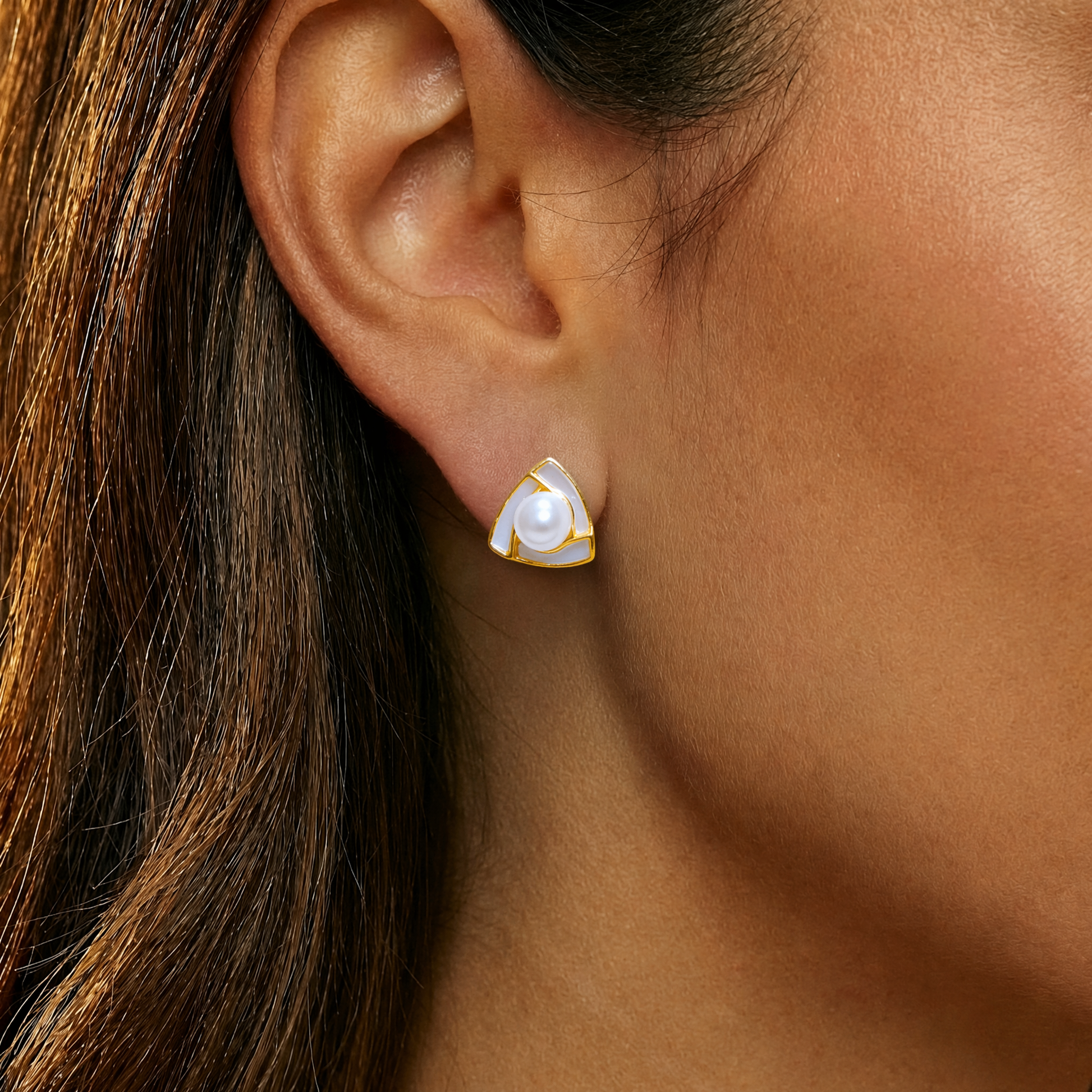 Close-up of an ear wearing a gold and pearl earring
