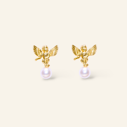 Gold angel earrings with pearl drops on a beige background