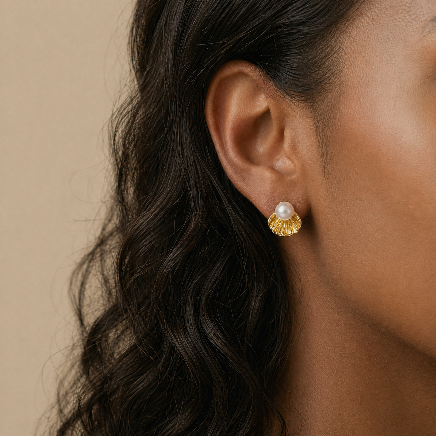 Close-up of an ear wearing a gold earring with a pearl 