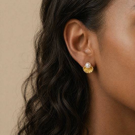 Close-up of an ear wearing a gold earring with a pearl 