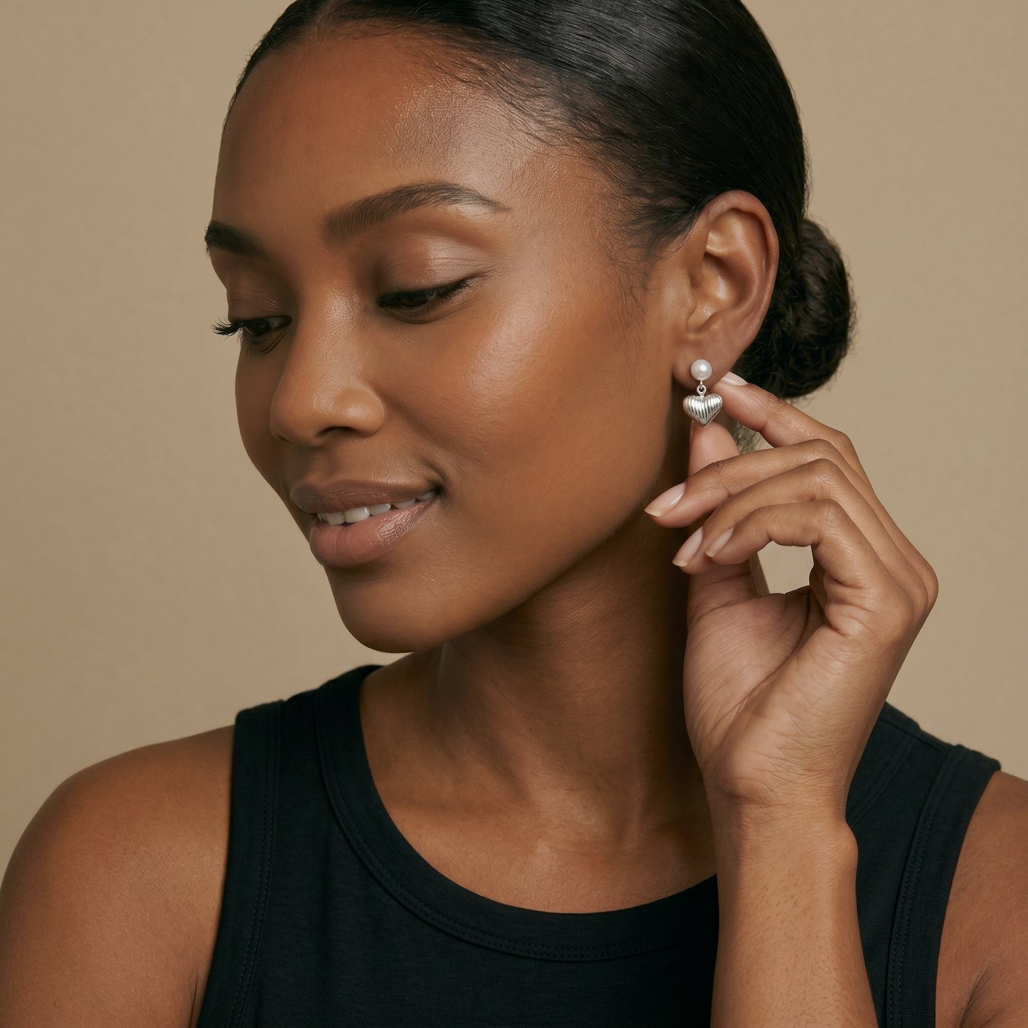 Woman wearing pearl earrings against a beige background