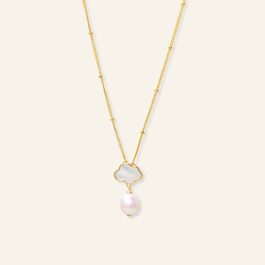 Gold necklace with a pearl pendant on a light beige background