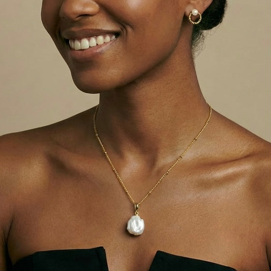 Woman wearing a gold necklace with a pearl pendant 