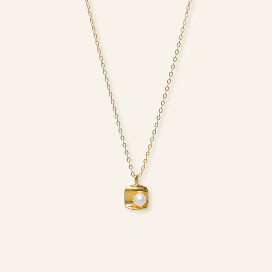 Gold necklace with a square pendant featuring a pearl 