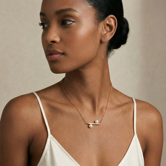 Woman wearing a delicate gold necklace with a pearl pendant 