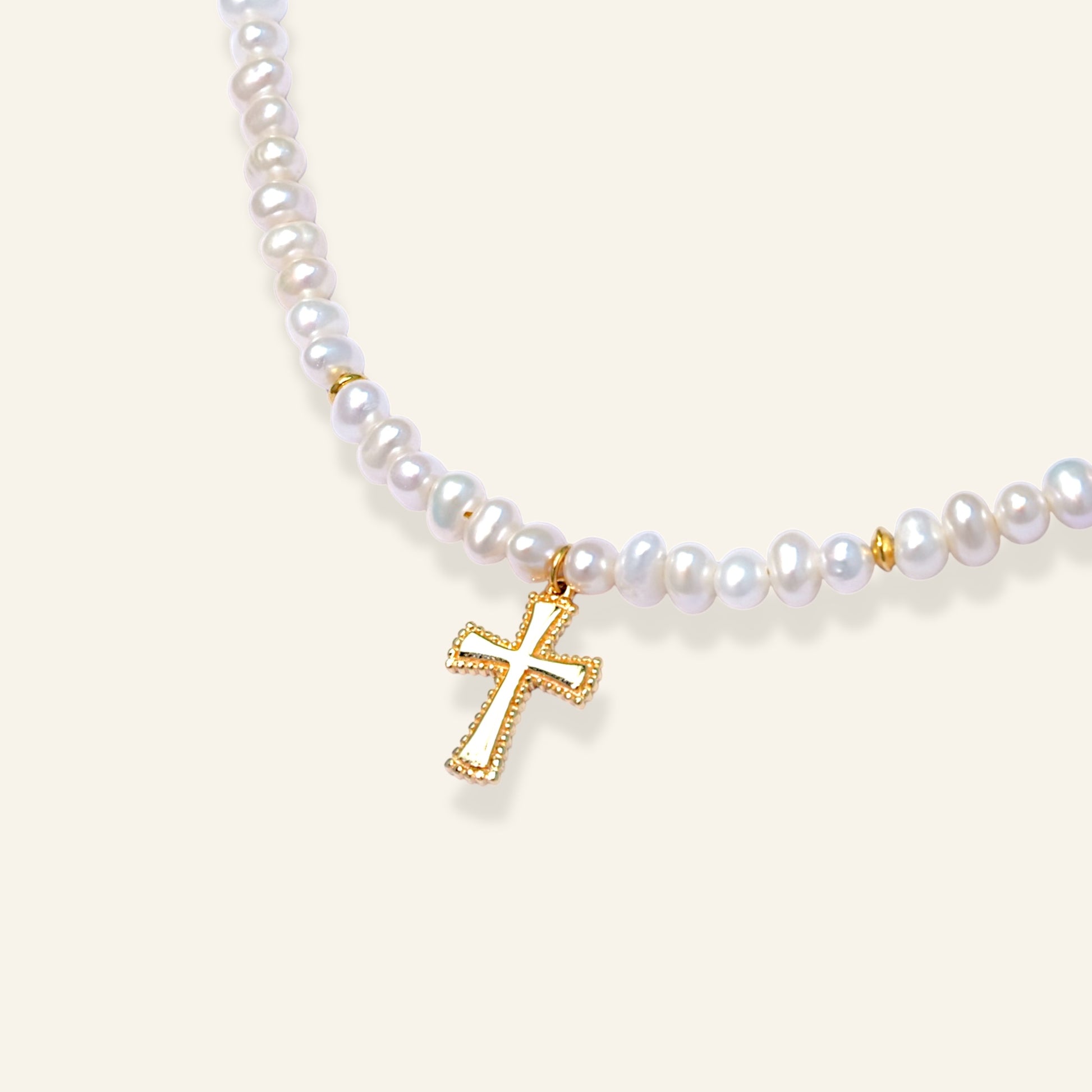 Pearl necklace with a gold cross pendant on a light background
