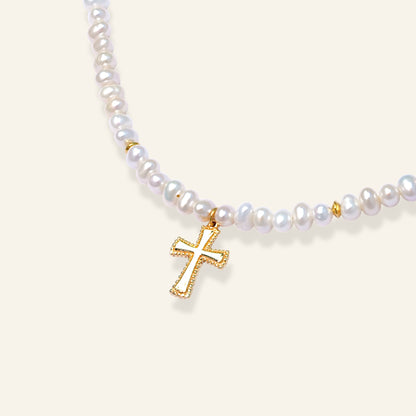 Pearl necklace with a gold cross pendant on a light background