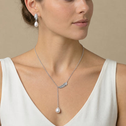 Model wearing a delicate freshwater pearl pendant necklace with a feather-inspired metal detail and a single white pearl.
