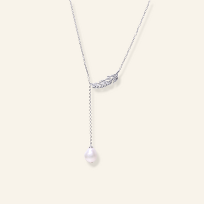 Freshwater pearl pendant necklace with a delicate feather-inspired metal detail and a single white pearl on a fine chain.