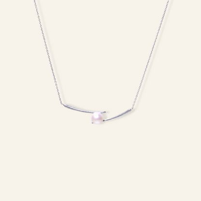 Gold freshwater pearl necklace with a single round white pearl set between two curved 18K gold plated bar details on a fine chain.